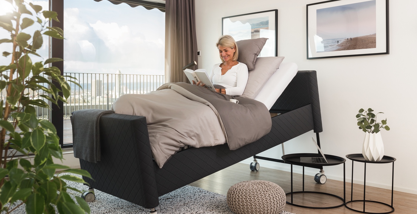A senior reading on a positioning bed